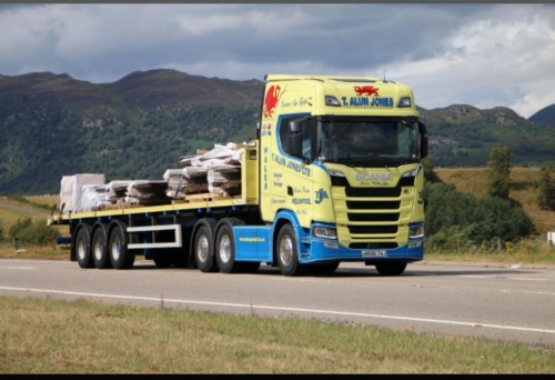 Surrounded by the rolling hills of Mid Wales, a T Alun Jones lorry hauling timber driving on the road