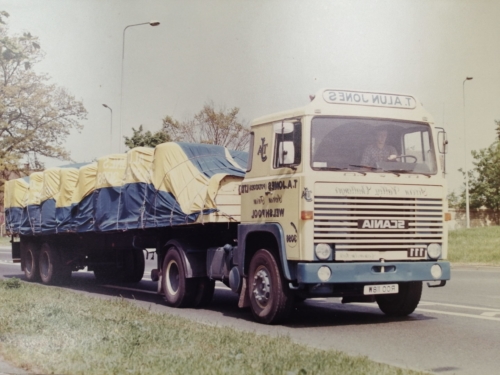 A driver with a checked shirt hauling some wood on a T Alun Jones truck